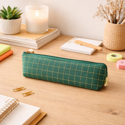 Hand holding portable green grid pencil pouch for travel or school.