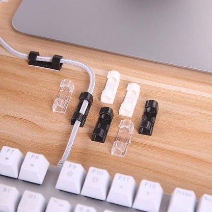 Plastic cable clips holding computer wires securely under a desk, improving office organization.