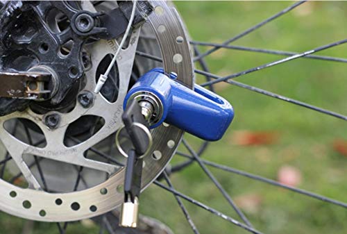 A blue motorcycle wheel security device is locked onto a bicycle's disc brake, with keys hanging from the lock cylinder.