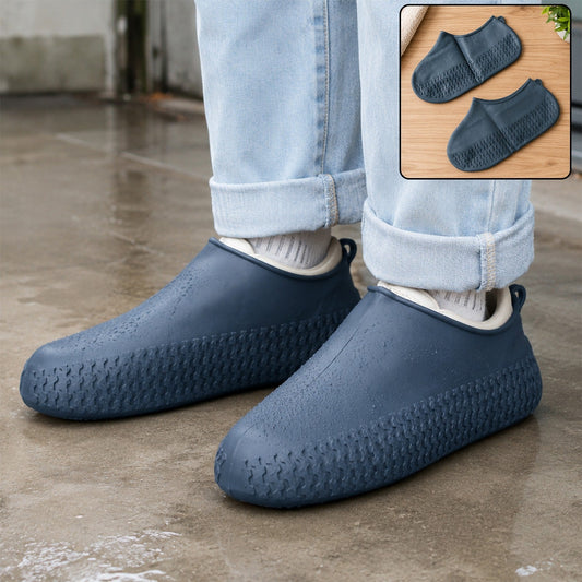 A person wears navy blue silicone shoe covers over their shoes, standing on a wet surface with two covers shown in an inset.