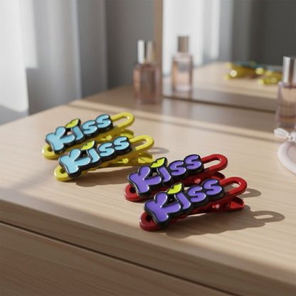 Three Kiss text hair clips arranged on a light background