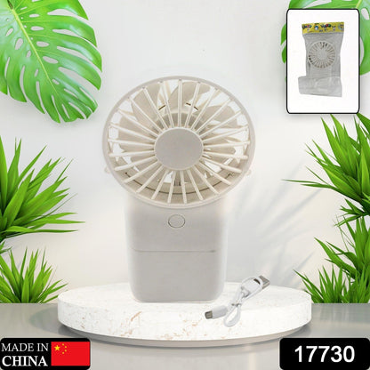 A person's hand holding the compact USB rechargeable fan for on-the-go relief.
